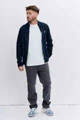 Cardigan de punto color azul marino, con cierre frontal completo, cuello alto y puños acanalados. Presenta un pequeño bordado distintivo en el pecho.