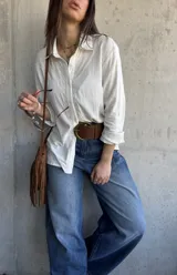 Camisa de color natural, manga larga, con detalle de bordado geométrico a lo largo de la botonadura frontal y cuello clásico.