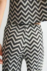 Pantalón de tiro alto confeccionado en punto jacquard con diseño de zigzag en blanco y negro. Presenta un corte de pierna amplia y cintura elástica.