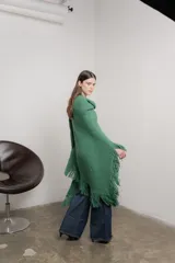 Poncho tejido color verde con cuello alto y flecos largos.