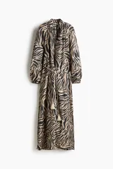 Vestido túnica largo de mezcla de viscosa con estampado de cebra, diseño oversized, cuello elevado con frunces, escote en V y mangas globo largas con puños elásticos. Incluye un cinturón fino para atar con borlas y tajos laterales.