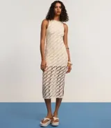 Vestido midi de crochet color crudo, sin mangas y con cuello redondo. Presenta aberturas laterales en el ruedo.