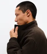 Campera bomber puffer de color marrón oscuro, confeccionada en poliéster con acabado texturizado. Presenta cuello alto, cierre frontal con cremallera, puños y ruedo elásticos.