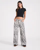 Pantalón de jean de corte recto y tiro medio, con estampado tipo camuflado de ramas en tonos grises y blancos.