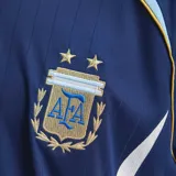 Camiseta de fútbol Adidas de la Selección Argentina, modelo visitante de la temporada 2006. Es de color azul marino con detalles en celeste y blanco, cuello redondo y el número 19 estampado en el frente. Incluye el logo de Adidas y el escudo de la AFA con dos estrellas.