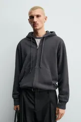 Sudadera de corte relajado confeccionada en tejido compacto de algodón con interior forrado, cuello con capucha, manga larga, bolsillos frontales tipo canguro y acabados en rib.
