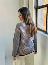 Sweater de punto con diseño estampado abstracto en tonos gris y beige, cuello redondo y terminaciones en color negro.