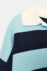Jersey de punto con cuello polo color crema, escote en V y manga larga. Diseño de rayas horizontales en azul claro y azul marino.