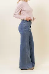 Pantalón de jean estilo wide leg, color celeste claro, con tiro medio, cinco bolsillos y cierre frontal con botón y cremallera.