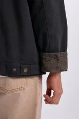 Campera gris oscuro de lona, con cuello camisero de pana en tono contrastante y cierre frontal con cremallera metálica.