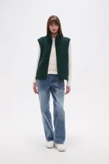 Chaleco sin mangas de textura peluche (teddy) color crema, con cuello alto y cierre frontal de cremallera.