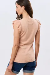 Remera tejida de algodón en color beige, de cuello redondo, sin mangas y con detalles de volados estructurados en los hombros.