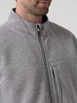 Polar de hombre color gris robusto, con cuello alto y cierre frontal. Presenta un bolsillo vertical con cierre en el pecho y bolsillos laterales con cierre. El tejido es de punto jaspeado.