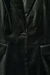 Blazer entallada de Zara Woman Collection confeccionada en tejido de terciopelo. Presenta cuello con solapas de muesca, manga larga con hombreras, bolsillos delanteros con solapa y cierre frontal con un botón. Incluye forro interior.