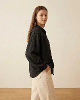 Camisa de calce amplio color verde oliva, con cuello camisero, hombros caídos y mangas largas con puños elásticos. Presenta detalle de frunce en el delantero y espalda, con cierre frontal de botones.