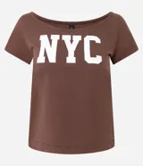 Remera de algodón color marrón oscuro con escote amplio tipo barco u hombro a hombro y manga corta. Presenta el estampado en mayúsculas "NYC" en color blanco en el frente.