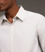 Camisa de vestir masculina de manga larga, confeccionada en tricolina con un sutil estampado de cuadros grid. Presenta cuello clásico, abotonadura frontal y puños con botones.