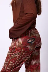 Pantalón de corte recto con estampado de líneas verticales en tonos tierra, rojizos y beige. Presenta bolsillos traseros con un logo bordado en color negro.