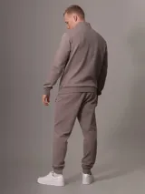 Buzo color topo de Calvin Klein, con cuello alto y media cremallera negra.