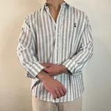 Camisa de manga larga a rayas verticales grises y blancas, con cuello clásico y cierre frontal con botones.