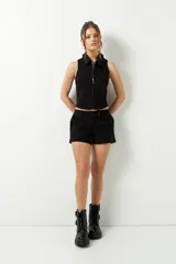 Top negro sin mangas, elastizado, con cuello tipo polo y cierre metálico frontal.