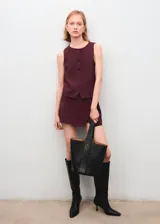 Chaleco de corte recto y diseño sin mangas, con cuello redondo y cierre frontal mediante botones. Presenta un estilo clásico y estructurado, ideal para combinar en conjuntos formales.