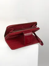Billetera grande de cuero vacuno con textura granulada y detalles en charol. Cuenta con múltiples ranuras para tarjetas y cierre de solapa con broche a presión grabado con el logo de la marca.
