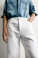 Jeans relaxed fit color blanco, de corte recto y tiro medio con tejido de algodón rígido. Cuenta con cinco bolsillos, efecto ligeramente lavado, perneras con raya de planchado y cierre frontal con cremallera y botón.