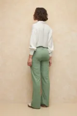Pantalón de lino color verde, de tiro alto, con bolsillos en el frente y atrás, y corte recto.