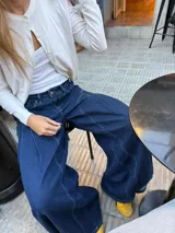 Jean ancho azul de corte wide leg, con diseño de costuras curvas decorativas en la parte delantera y tiro bajo.