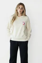 Buzo crudo con capucha y bolsillo tipo canguro, con estampado de ají y la frase "Spice it up" en el pecho.