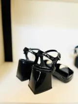 Sandalias de cuero charol negro con plataforma delantera y taco cuadrado.