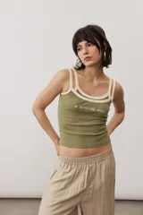 Musculosa de tejido acanalado color verde militar con doble tirante y ribetes en color crudo. Presenta un estampado de texto en el pecho.