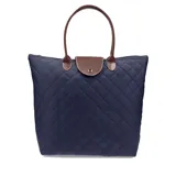 Cartera tipo bolso de diseño capitoneado con patrón de rombos, color azul marino. Cuenta con cierre superior, solapa frontal con broche metálico y asas cortas de mano en color marrón.