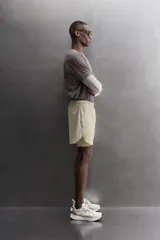 Short de running 2 en 1 color beige, confeccionado en tejido técnico ligero y elástico con malla interior integrada. Presenta cintura elástica ajustable con cordón, bolsillo trasero con cierre y aberturas laterales en el bajo.