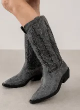 Bota de estilo texano confeccionada en cuero genuino, con caña alta y diseño de costuras decorativas en contraste. Presenta punta fina y taco cuadrado de madera.