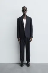 Blazer de corte regular fit confeccionado en tejido con lana. Presenta cuello con solapas de muesca, cierre frontal de un botón, bolsillos de vivo en el pecho y en la cadera, y aberturas en la espalda.