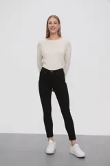 Pantalon de jean negro, corte skinny y tiro medio, con cierre frontal y bolsillos laterales.