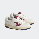 Championes Vans modelo Upland de estilo retro inspirado en los años 90. Presentan una base de ante color blanco con detalles en azul marino y rojo en el logotipo lateral en forma de V. Cuentan con una suela cupsole gruesa en tono crema, cordones anchos y cuello acolchado para mayor comodidad.