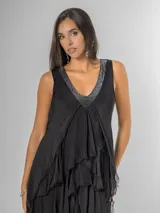 Vestido largo negro de seda con escote en V adornado con lentejuelas plateadas. Presenta un diseño de capas superpuestas con terminaciones deshilachadas que aportan volumen y movimiento. Es de corte sin mangas con breteles anchos y espalda elastizada.