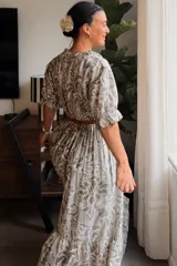 Vestido largo celeste con estampado paisley y floral en tonos azul oscuro, escote en V con cuello con volados, mangas cortas abullonadas y falda amplia con volado en el ruedo.