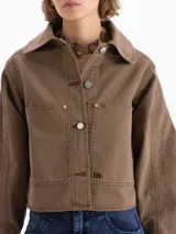 Chaqueta de gabardina color marrón, con cuello camisero, cierre frontal con botones metálicos, bolsillos frontales y mangas abullonadas con puños rectos.