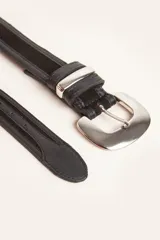 Cinturón de cuero negro con detalles en gamuza, presenta una hebilla metálica plateada de diseño redondeado y pasador metálico a juego.
