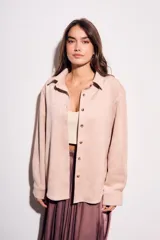 Camisa color marrón de gamuza sintética, de corte recto, con cuello clásico, cierre frontal con botones y mangas largas.