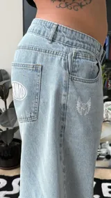 Pantalón de jean estilo baggy, color celeste claro, de tiro alto y corte amplio con detalles bordados en los bolsillos.