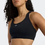 Top deportivo New Balance Essential negro, de soporte medio, con tirantes anchos y espalda deportiva. Presenta el logo NB en el centro del pecho.