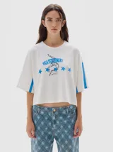 Remera cropped de algodón con efecto lavado, cuello redondo y mangas cortas con franjas laterales verticales. Presenta estampa frontal con texto y diseño gráfico.
