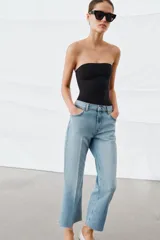 Jeans de tiro medio con corte flare y largo cropped. Presentan diseño de cinco bolsillos, cierre frontal con cremallera y botón, raya planchada en el delantero y bajo desflecado con acabado evasé.