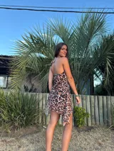 Vestido corto con estampado abstracto en tonos rosados, escote en V y breteles finos que se atan al cuello. Tiene corte en la cadera y falda con ruedo irregular y pico en lateral.