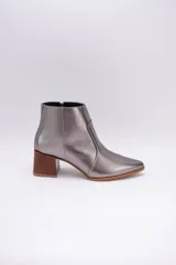 Botas cortas de cuero color beige, con punta fina y cierre lateral. Tienen un taco cuadrado de madera.